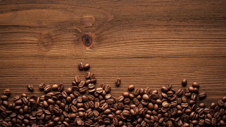 black coffee grains lie on a brown wooden table, background image