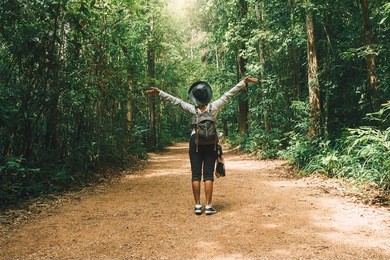 traveler woman with backpack walking on path in the tropical forest, krabi, thailand