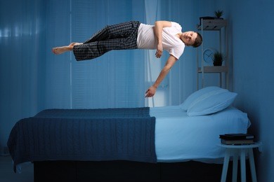 sleep paralysis concept. young man levitating over bed