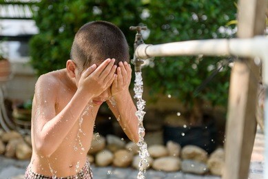 close up young asian boy taking water from old faucet in the garden. water shortage and drought concept