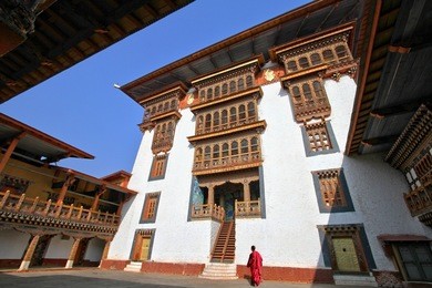 monk walking in paro rinpung dzong, buddhist monastery and fortress on a hill near the paro chu river. bhutanese style building decorated with carved wood window frames at rinpung dzong, bhutan.