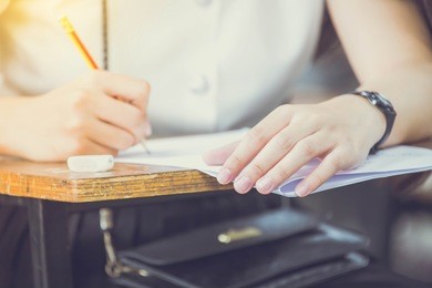soft focus undergraduate student holding pencil and sitting on row chair doing final exam attending in examination room or classroom.university student in uniform.