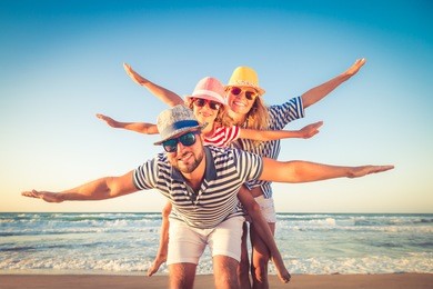 happy family on the beach. people having fun on summer vacation. father, mother and child against blue sea and sky background. holiday travel concept