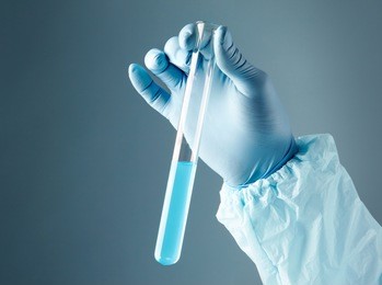 close-up of glass tube with blue fluid in scientist hand during medical test