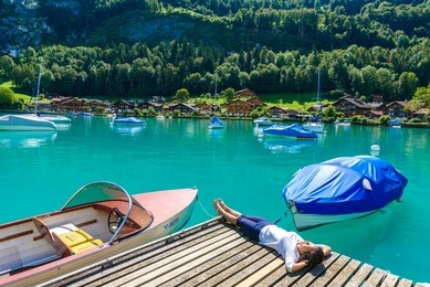 girl at boats in bay of village iseltwald at lake brienz - beautiful lake in the alps at interlaken, switzerland