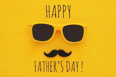 father's day concept. hipster yellow sunglasses and funny moustache on wooden background