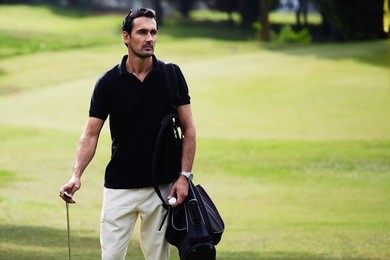 half length portrait of handsome man standing on the golf course. professional golf player luxury recreation during game