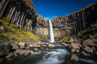 svartifoss in iceland. dramatic waterfall surrounded by black basalt lava hexagonal columns.