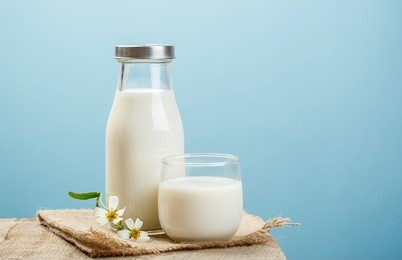 two glass of milk with flower on a wooden table in a blue background, nutritious and healthy dairy products concept
