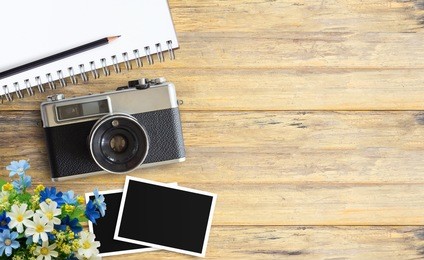 top view image of blank notebook and vintage camera with two blank photo frames on wood table or office desk background. space for design