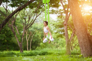 beautiful girl practicing fly-yoga at the tree .advanced yoga