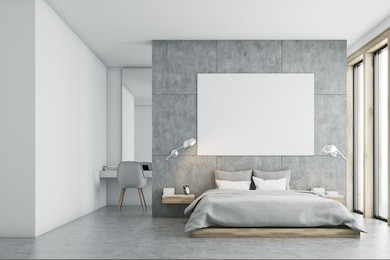 gray bedroom interior with a panoramic window, a double bed standing along it and a large horizontal poster hanging above. a home office is in the background. 3d rendering, mock up