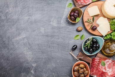 typical italian antipasto, wooden cutting board with prosciutto, ham, cheese and olives on black background. top view with copy space