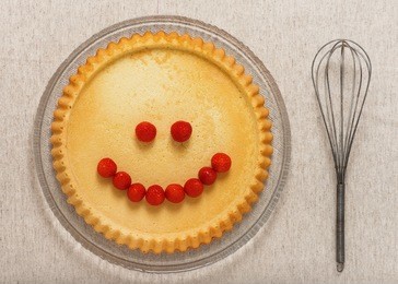 top view of biscuit sponge cake and steel whisk. dessert that makes you smile. creative baked food concept. 
