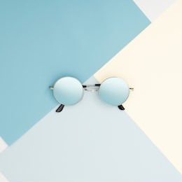 minimal style. minimalist fashion photography. fashion summer is coming concept. blue glasses on a blue background, top view. trendy minimal style with colorful paper backdrop