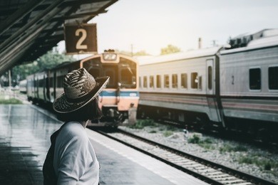 summer travel,hipster travel are waiting for the train at the platform of railway station. travel concept.