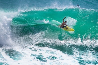 surfer riding big wave at padang padang beach, bali, indonesia