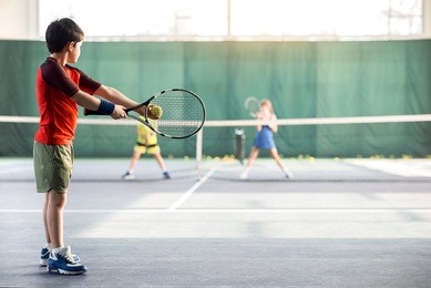 concentrated boy pitching tennis ball