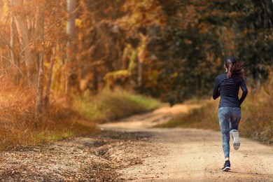 young woman running on a trail running track in autumn season with copy space, healthy lifestyle and sport concept.