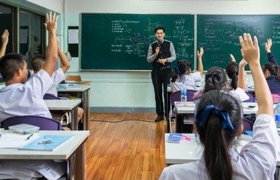 asian teacher giving lesson over the the physics formula in thai language on black board in school classroom and students showing the hand for answer,school education concept,the teacher wrote himself