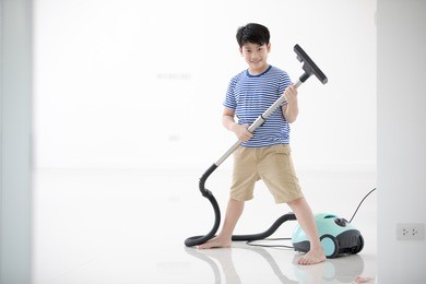 happy asian child cleaning in the house. a little boy with dust vacuumed the floor.
