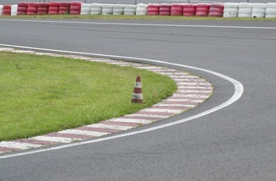 sleek asphalt and danger at the bend of the motorbike track and red orange striped cones, motogp