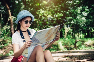 beautiful woman backpacker resting and reading a map in the forest - travel and lifestyle concept in holiday summer