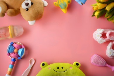 colourful soft baby toys on pink background with copy space, top view.