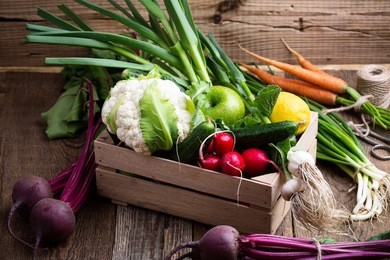 organic  farm. fresh vegetables in crate,   cauliflower, garlic, radishes and cucumbers on rustic wooden background 