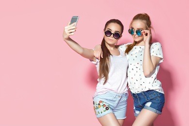 two young female friends embracing and posing for selfie together.