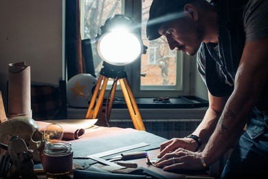 caucasian leather man working as artisan in his workshop. low key photo