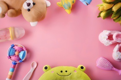 colourful soft baby toys on pink background with copy space, top view.