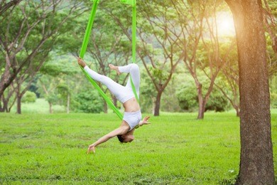 beautiful girl practicing fly-yoga at the tree .advanced yoga
