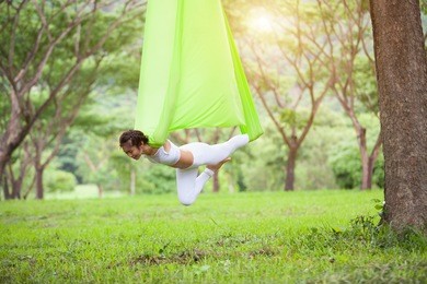 beautiful girl practicing fly-yoga at the tree .advanced yoga