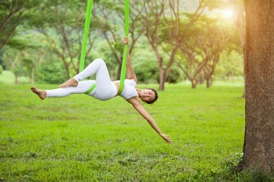 beautiful girl practicing fly-yoga at the tree .advanced yoga
