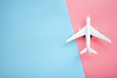 flat lay design of travel concept with plane on blue and pink background with copy space.