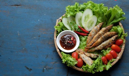 vietnamese food for family meal at lunch or dinner, fried fish with tamarind sauce and green vegetable, delicious food homemade on wooden background