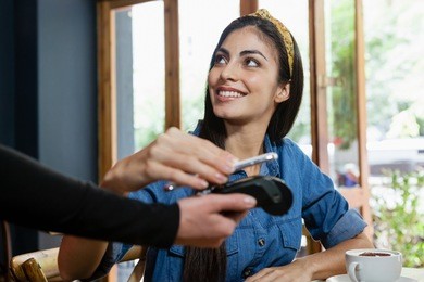 smiling woman making payment on credit card reader at cafe shop