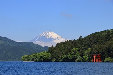 mt. fuji and a big red torii (gate to the hakone shrine) on the ashinoko lake under a clear sunny sky. photoed in hakone, japan.
