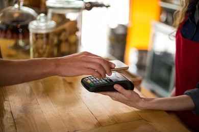 man paying bill through smartphone using nfc technology in cafe