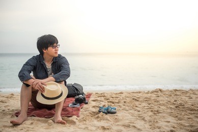 young asain man sitting on tropical beach and see the beautiful sunset, happy vacation time and summer holiday travel concepts