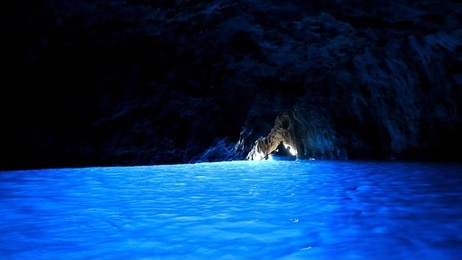 a silhouette of a boat at the exit of blue grotto cave, capri, italy