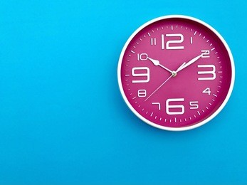 closeup pink wall clock  set on blue background. the concept of " the time is going on." top view with selective focus. copy space.