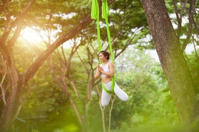 beautiful girl practicing fly-yoga at the tree .advanced yoga