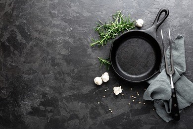 empty cast iron frying pan on dark grey culinary background, view from above