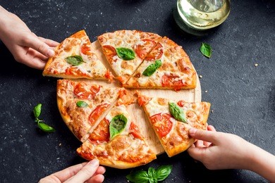 people hands taking slices of pizza margherita. pizza margarita and  hands close up over black background.