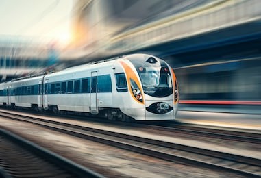 high speed train in motion at the railway station at sunset in europe. modern intercity train on the railway platform with motion blur effect. industrial scene with moving passenger train on railroad