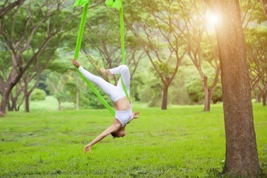 beautiful girl practicing fly-yoga at the tree .advanced yoga