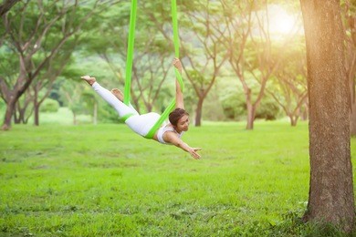 beautiful girl practicing fly-yoga at the tree .advanced yoga