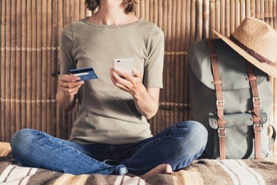 young woman on vacations using smartphone and credit card. online shopping and travel concept
